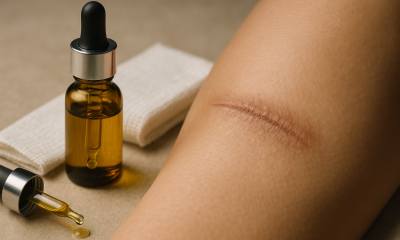 A cinematic widescreen photo showing a glass dropper bottle of golden hemp seed oil next to folded gauze, with a close-up of a healed scar on skin, symbolizing natural wound-healing research.