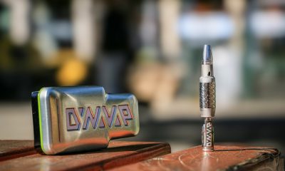 Close-up of a DynaVap thermal extraction device and metal case placed on a wooden surface outdoors, showcasing battery-free cannabis vaporizer design.