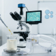 A high-tech laboratory setting showing a close-up of a golden cannabinoid oil droplet being added to a beaker of clear liquid, which is being processed by a modern, transparent microfluidizer to create a nanoemulsion.