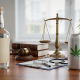 A photorealistic still life on a professional wooden desk comparing alcohol and cannabis. A bottle of brown liquor stands next to a silver beverage can labeled