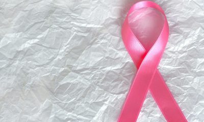 Pink breast cancer awareness ribbon on a white textured background symbolizing hope and support.